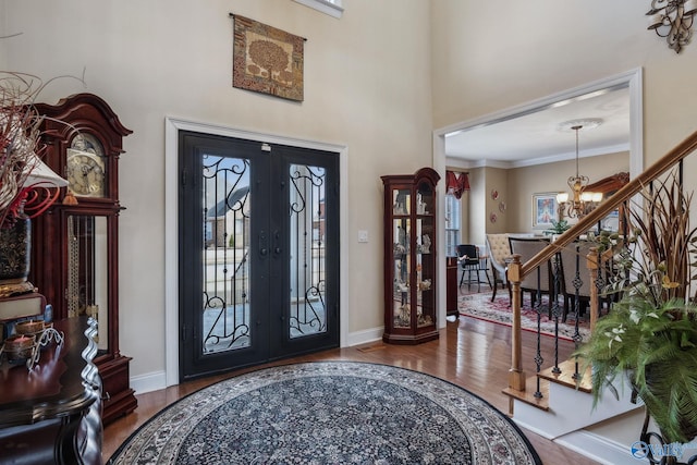 entrance foyer featuring baseboards, wood finished floors, a high ceiling, crown molding, and a notable chandelier