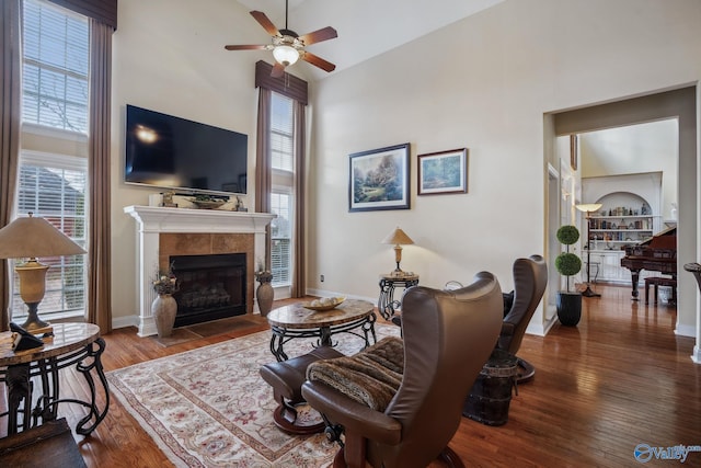 living room with baseboards, a fireplace, a high ceiling, and wood finished floors