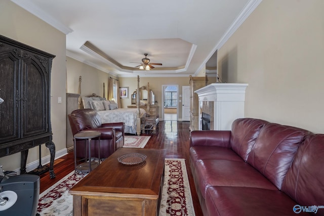 living room with dark wood-style floors, a raised ceiling, and crown molding