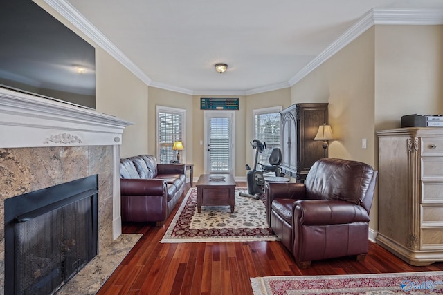 living area with ornamental molding, a premium fireplace, wood finished floors, and baseboards