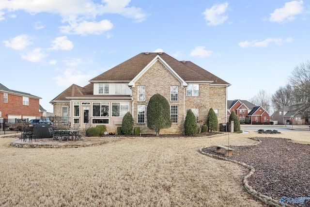 traditional-style home with a patio area, brick siding, and fence