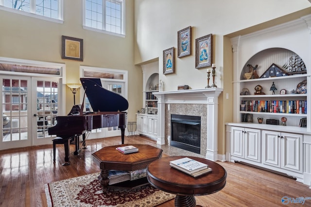 living area with hardwood / wood-style flooring, plenty of natural light, built in shelves, and a fireplace