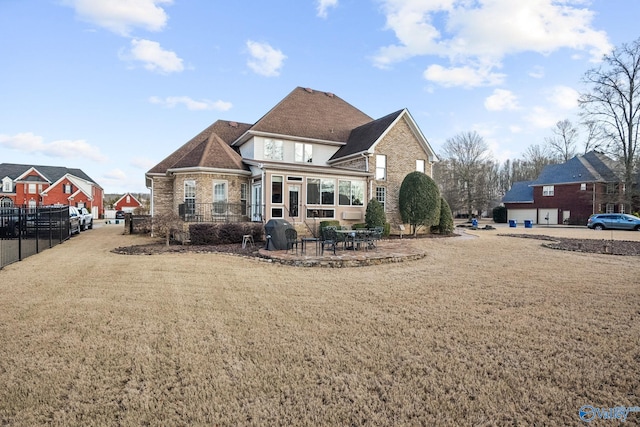 back of house featuring a patio, brick siding, a lawn, and fence