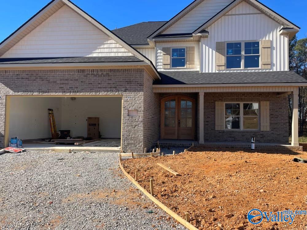 104 Ayers Spring Rd, New Market, AL 35761 - view of front of house with french doors, gravel driveway, brick siding, an attached garage, and covered porch