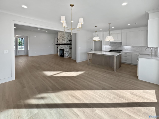 kitchen featuring light countertops, decorative backsplash, open floor plan, a sink, and light wood-type flooring