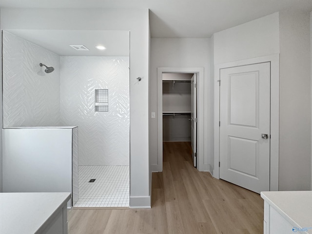 full bath featuring visible vents, wood finished floors, a spacious closet, vanity, and a walk in shower