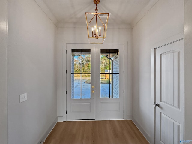 doorway to outside with french doors, baseboards, an inviting chandelier, and wood finished floors