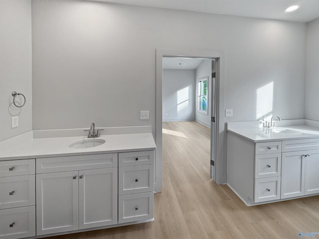 bathroom with recessed lighting, two vanities, a sink, and wood finished floors