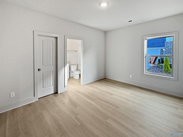 unfurnished bedroom with light wood-type flooring, baseboards, and ensuite bathroom