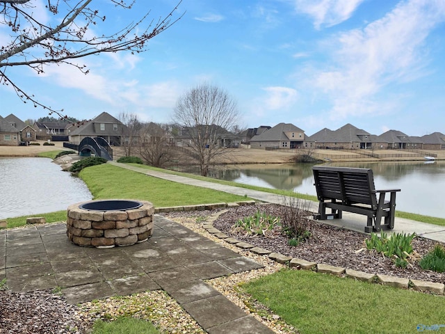 surrounding community with a yard, a water view, and an outdoor fire pit