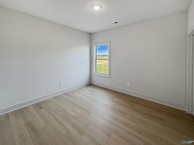 unfurnished room with light wood-type flooring, visible vents, and baseboards