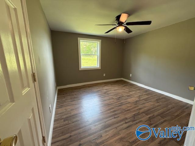 unfurnished room with baseboards, ceiling fan, and dark wood-style flooring