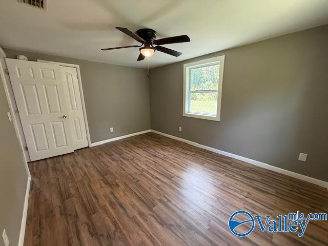 unfurnished bedroom featuring visible vents, ceiling fan, wood finished floors, and baseboards