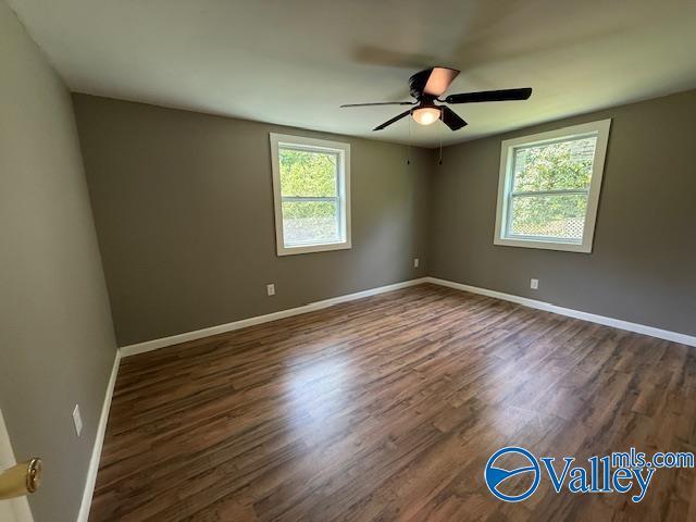 unfurnished room with dark wood finished floors, baseboards, and ceiling fan