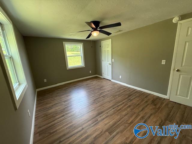 interior space featuring a textured ceiling, a ceiling fan, dark wood finished floors, and baseboards