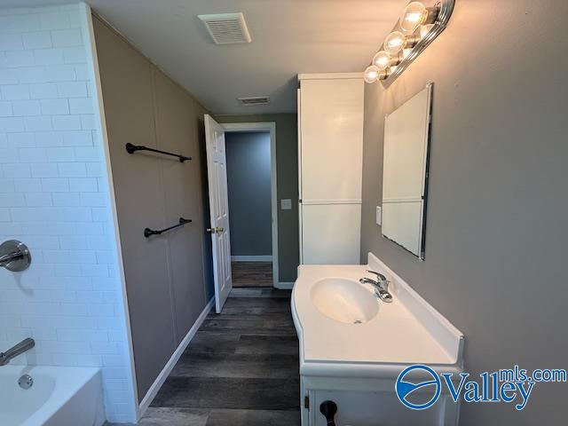 full bath with washtub / shower combination, visible vents, baseboards, wood finished floors, and vanity