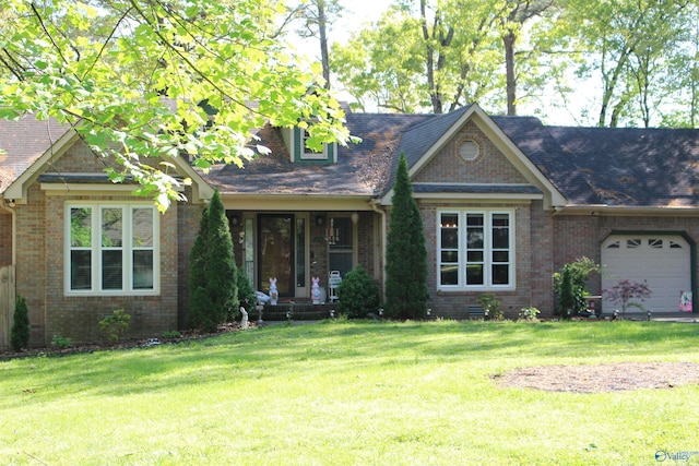 view of front of house featuring brick siding, an attached garage, a shingled roof, and a front yard