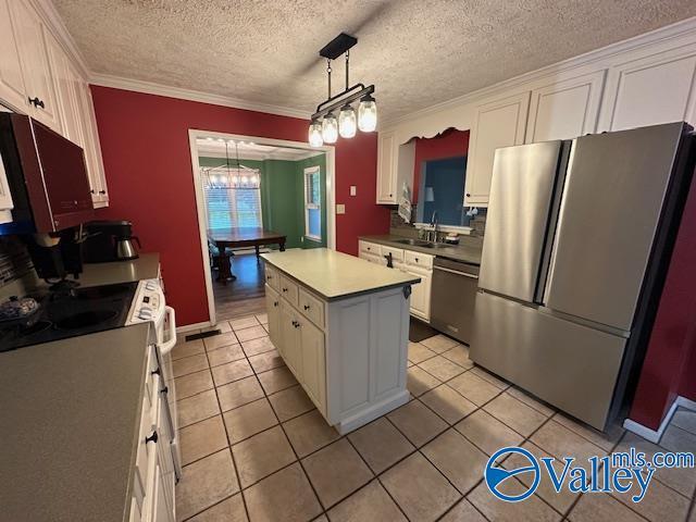 kitchen featuring light tile patterned floors, white cabinets, a center island, appliances with stainless steel finishes, and a sink