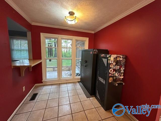 doorway with a textured ceiling, light tile patterned floors, crown molding, and visible vents
