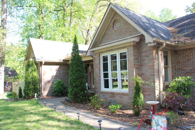 view of property exterior featuring brick siding and roof with shingles