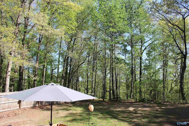 view of yard featuring a forest view and fence