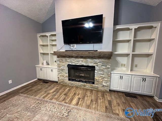 unfurnished living room featuring a fireplace, dark wood finished floors, a textured ceiling, lofted ceiling, and baseboards