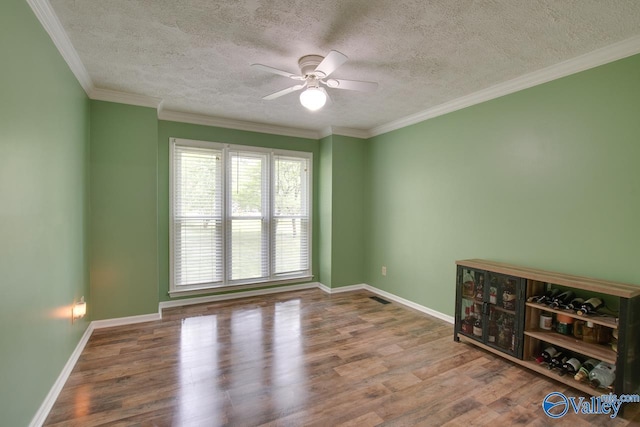 empty room featuring baseboards, a ceiling fan, wood finished floors, and a textured ceiling