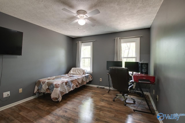 bedroom featuring wood finished floors, a textured ceiling, baseboards, and multiple windows