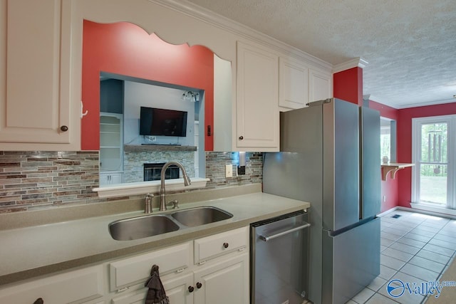 kitchen featuring a sink, tasteful backsplash, a textured ceiling, appliances with stainless steel finishes, and white cabinetry