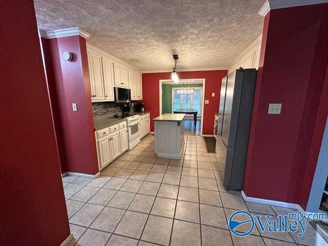 kitchen featuring crown molding, light tile patterned floors, freestanding refrigerator, white range with electric cooktop, and stainless steel microwave