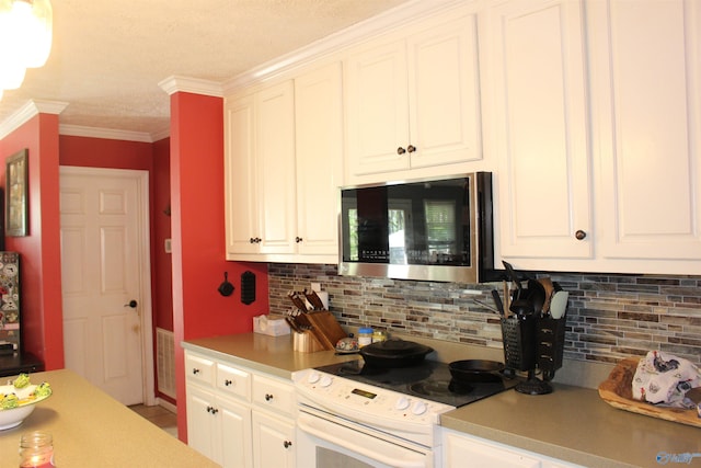 kitchen with stainless steel microwave, white cabinets, electric range, and backsplash