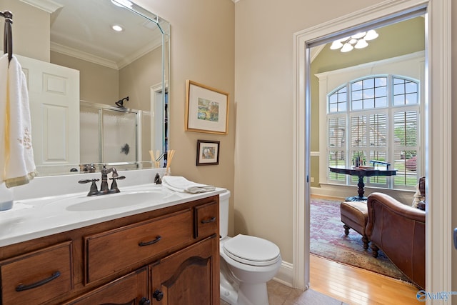 bathroom with vanity, crown molding, toilet, a shower stall, and wood finished floors