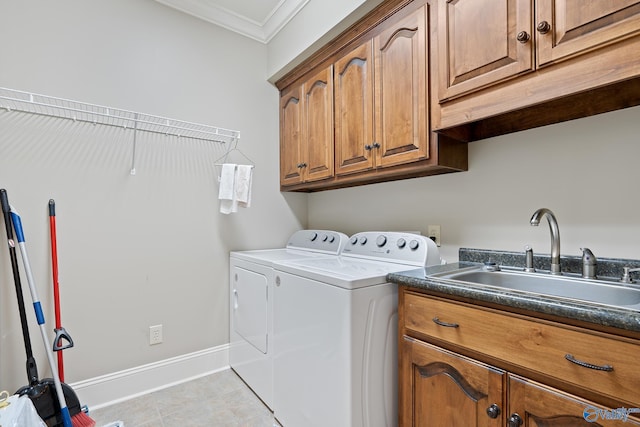 washroom featuring baseboards, a sink, ornamental molding, cabinet space, and washing machine and dryer