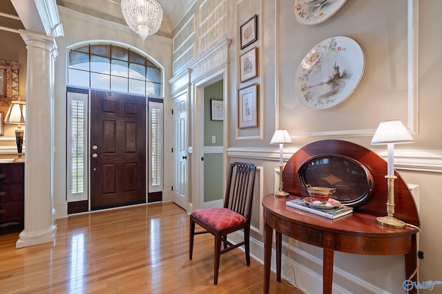 entryway featuring ornate columns, ornamental molding, wood finished floors, a high ceiling, and baseboards