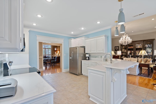 kitchen with crown molding, a peninsula, visible vents, light countertops, and stainless steel appliances