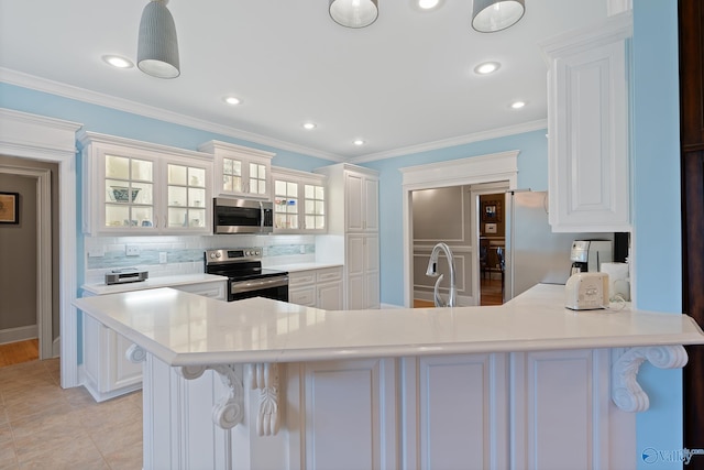 kitchen featuring white cabinets, light countertops, appliances with stainless steel finishes, a peninsula, and decorative backsplash