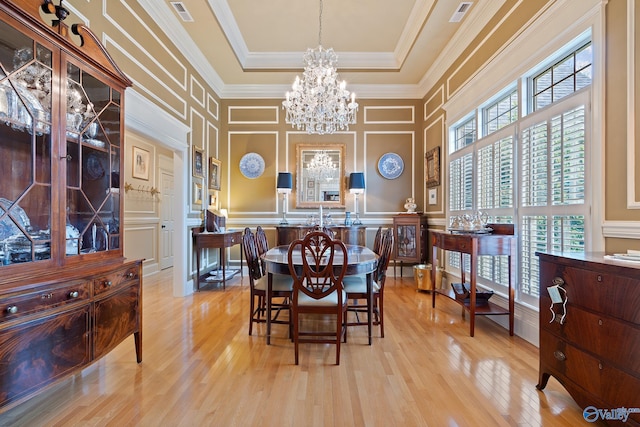 dining area with a decorative wall, visible vents, an inviting chandelier, and crown molding