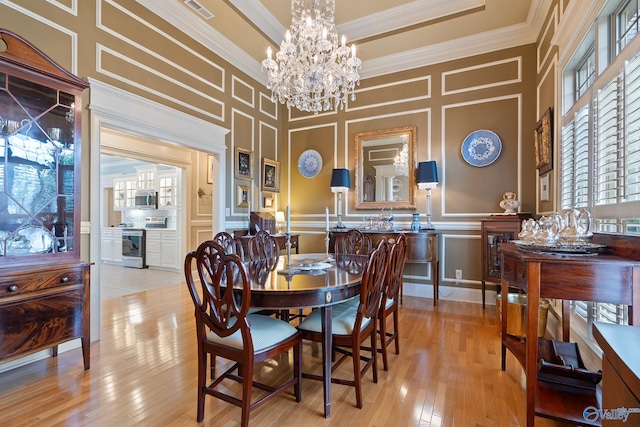dining space with a decorative wall, ornamental molding, light wood-style flooring, and visible vents