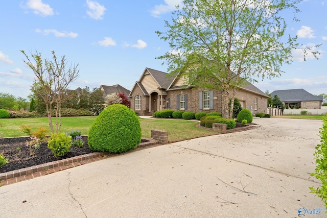 view of front of house featuring a front yard, brick siding, and driveway