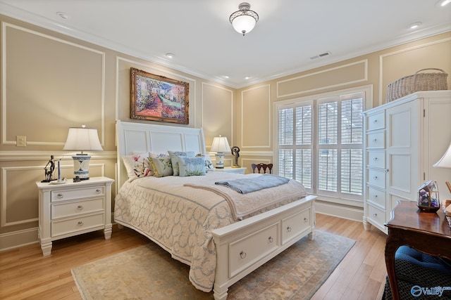 bedroom featuring a decorative wall, visible vents, light wood-style flooring, and crown molding