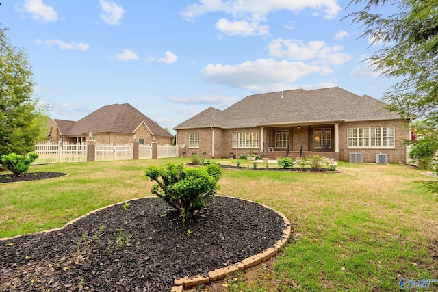 back of property with brick siding, fence, and a lawn