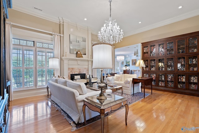 living area featuring visible vents, an inviting chandelier, a fireplace, crown molding, and light wood finished floors