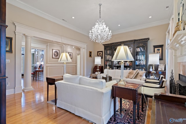 living area with light wood-style floors, ornate columns, and crown molding
