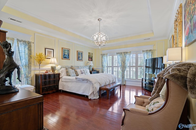 bedroom with a raised ceiling, a notable chandelier, dark wood-style flooring, a decorative wall, and crown molding