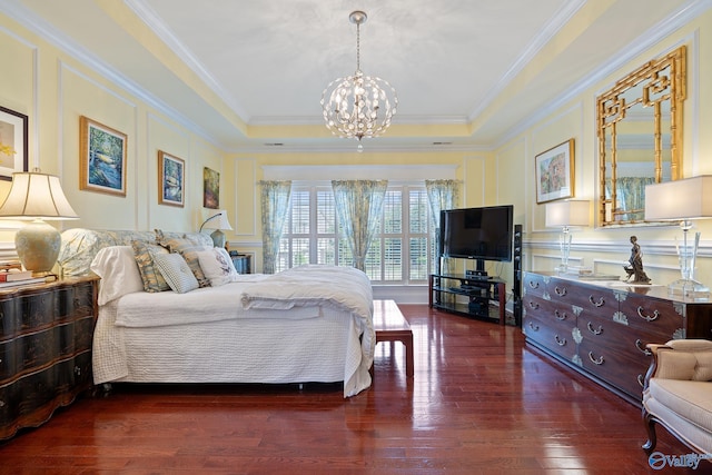 bedroom with a decorative wall, a tray ceiling, an inviting chandelier, and hardwood / wood-style flooring
