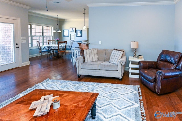 living area featuring visible vents, wood finished floors, baseboards, and ornamental molding