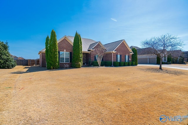 view of front of property with a garage, brick siding, driveway, and fence