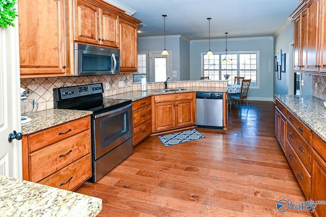 kitchen with decorative backsplash, a peninsula, light wood-style floors, stainless steel appliances, and a sink