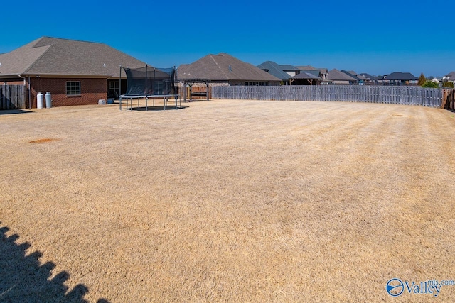 view of yard featuring a trampoline and fence