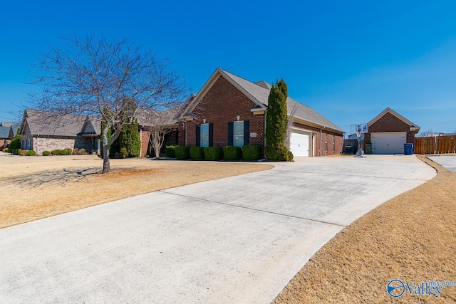 view of front of property featuring brick siding, an attached garage, concrete driveway, and fence